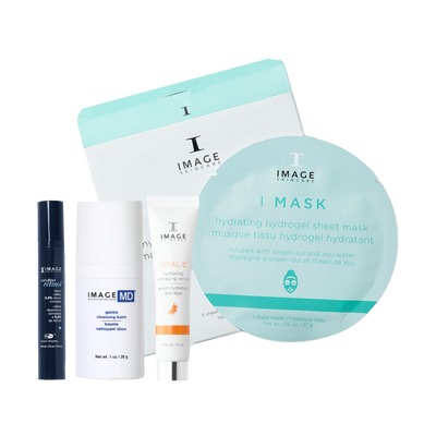 A skincare gift set from Image Skincare on a white background, featuring a large round sheet mask, a white and mint box, a white and orange tube, a white bottle, and a dark blue spray bottle.