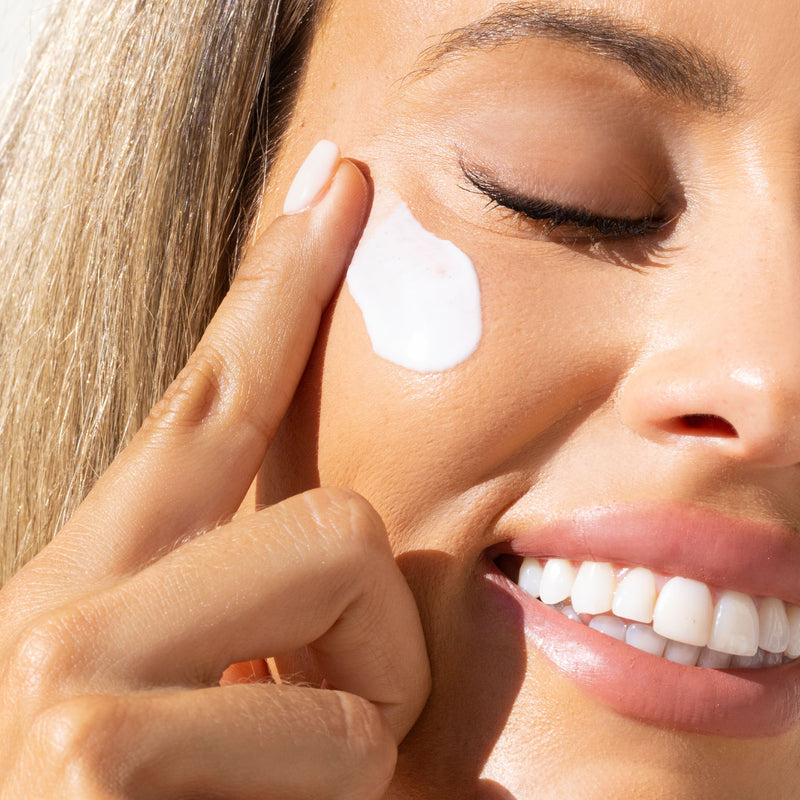 Woman using SPF moisturizer on her right cheek